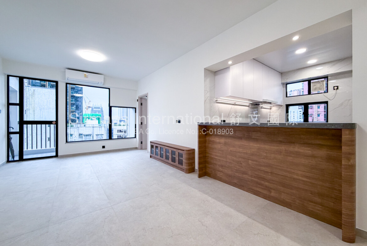 Vacant modern 2 bedrooms apartment interior with open-concept living area, abundant natural light from large windows offering urban city views, light gray porcelain floor tiles, minimalist white kitchen with wood-accent breakfast bar, and air-conditioning units