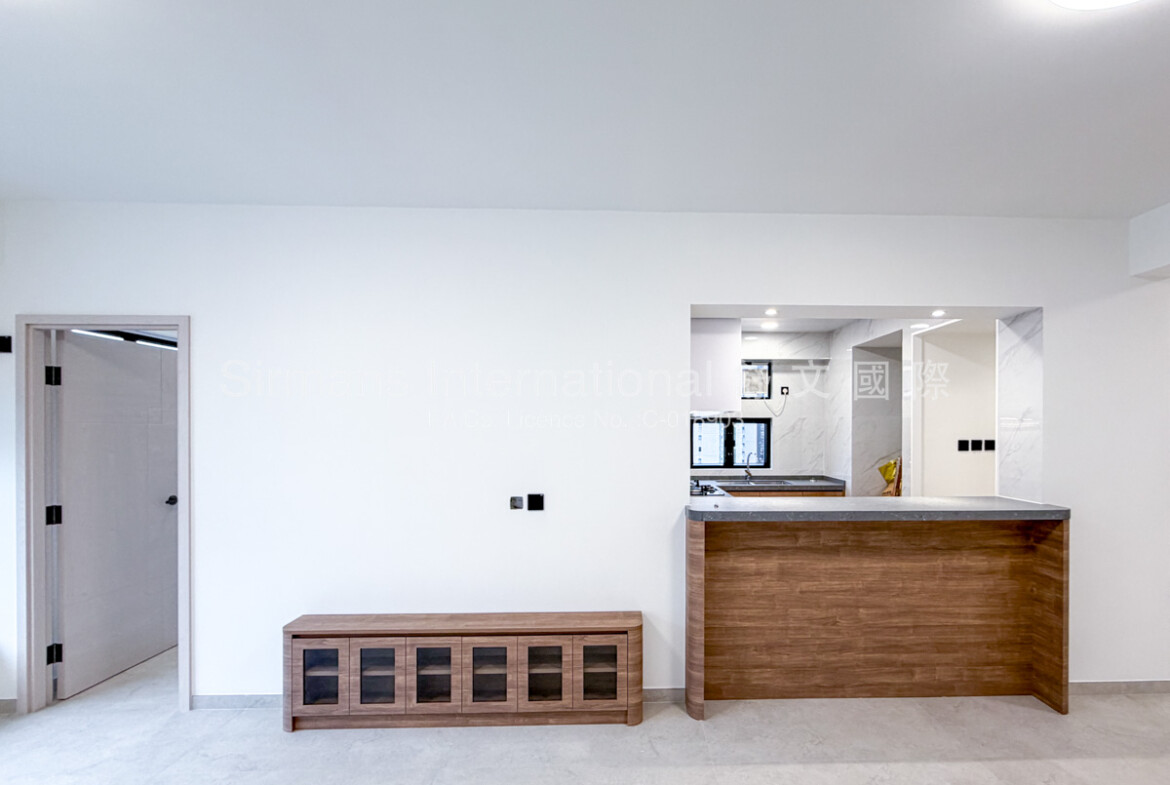 Empty bedroom in a newly renovated high-rise apartment, featuring light gray large-format porcelain floor tiles, crisp white walls, recessed ceiling lighting, a large black-framed corner window providing abundant natural light and direct views of surrounding urban high-rise buildings, a partially open light wood door leading to an en-suite or hallway, and a wall-mounted air-conditioning unit visible through the doorway.